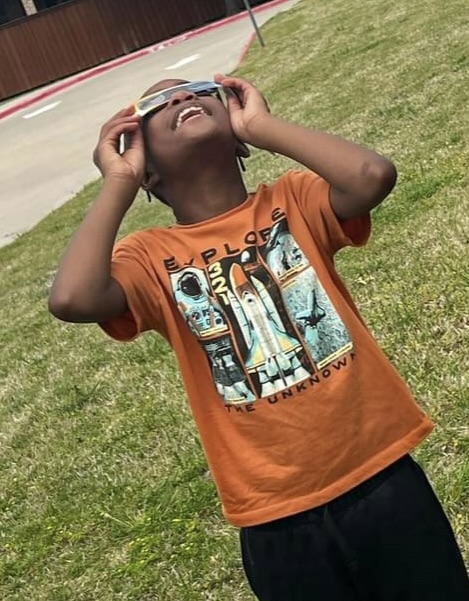 young boy looking up to the sky to see the solar eclipse